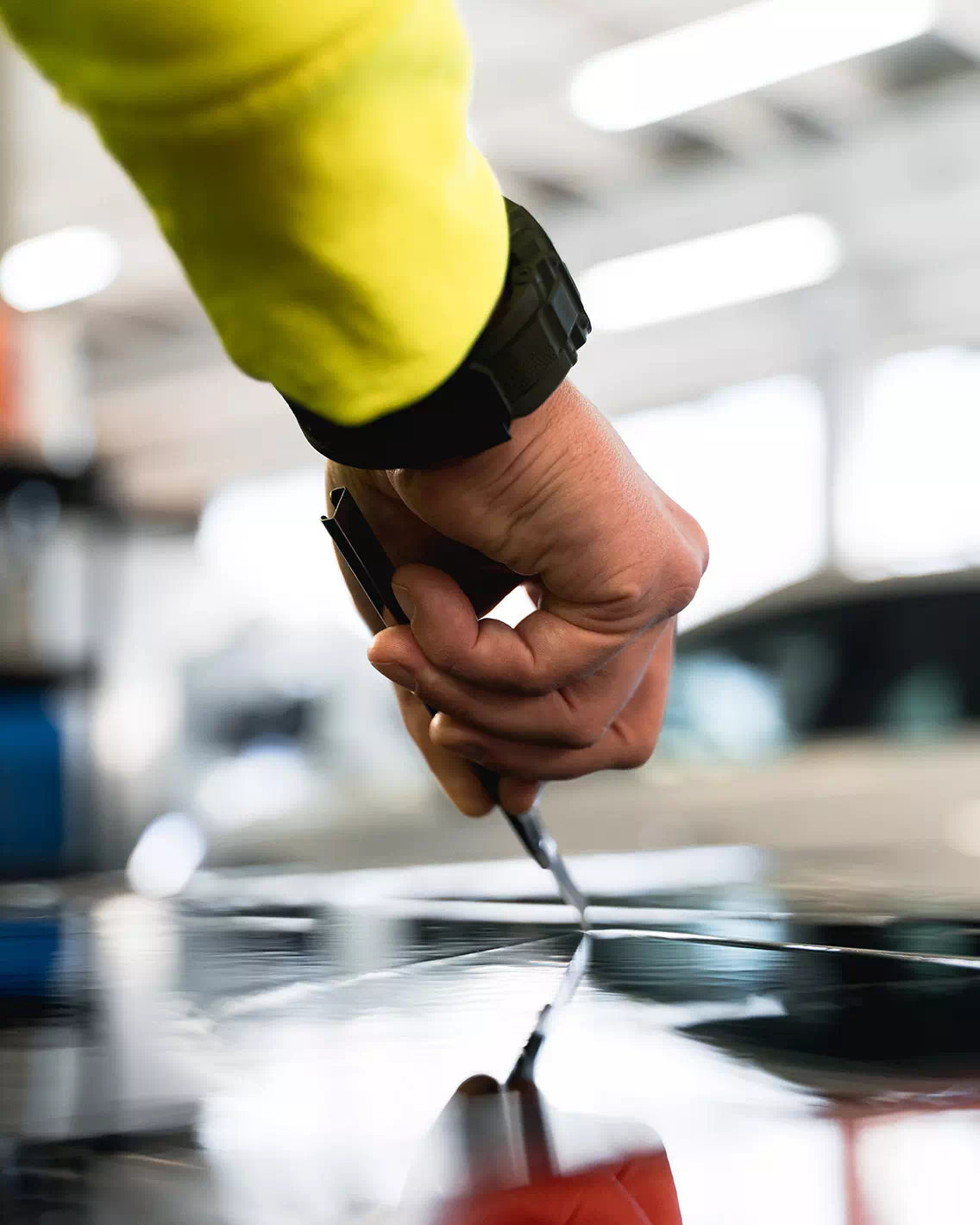 Mano di un operatore di Technoglass che effettua un lavoro di precisione per applicare pellicole oscuranti.