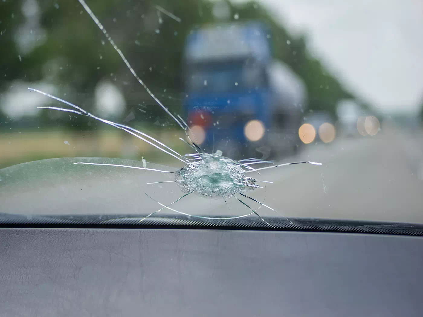 Primo piano del parabrezza rotto durante la guida in autostrada.