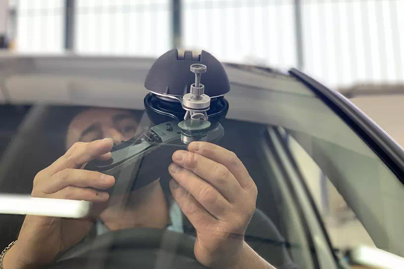 Primo piano di un operatore che lavora alla riparazione del parabrezza auto.