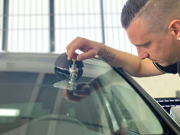 Primo piano operatore di Technoglass, attiva a Varese e Novara, che ripara un parabrezza.